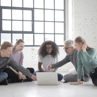 gruppo di persone discutono davanti ad un computer sedute per terra